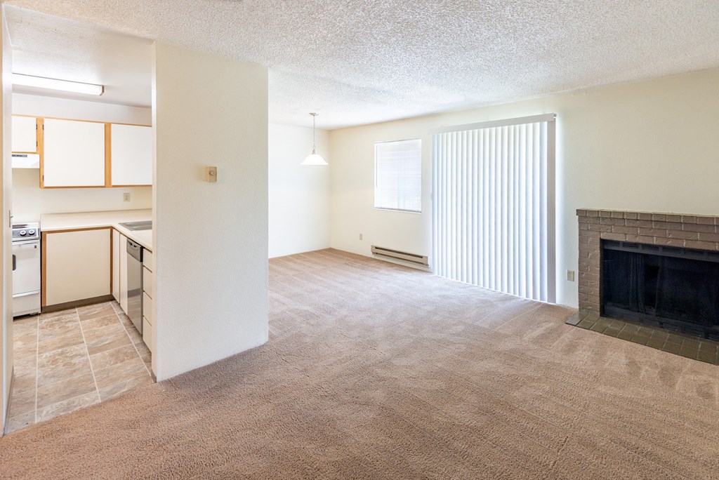a living room with a fireplace and a kitchen in the background