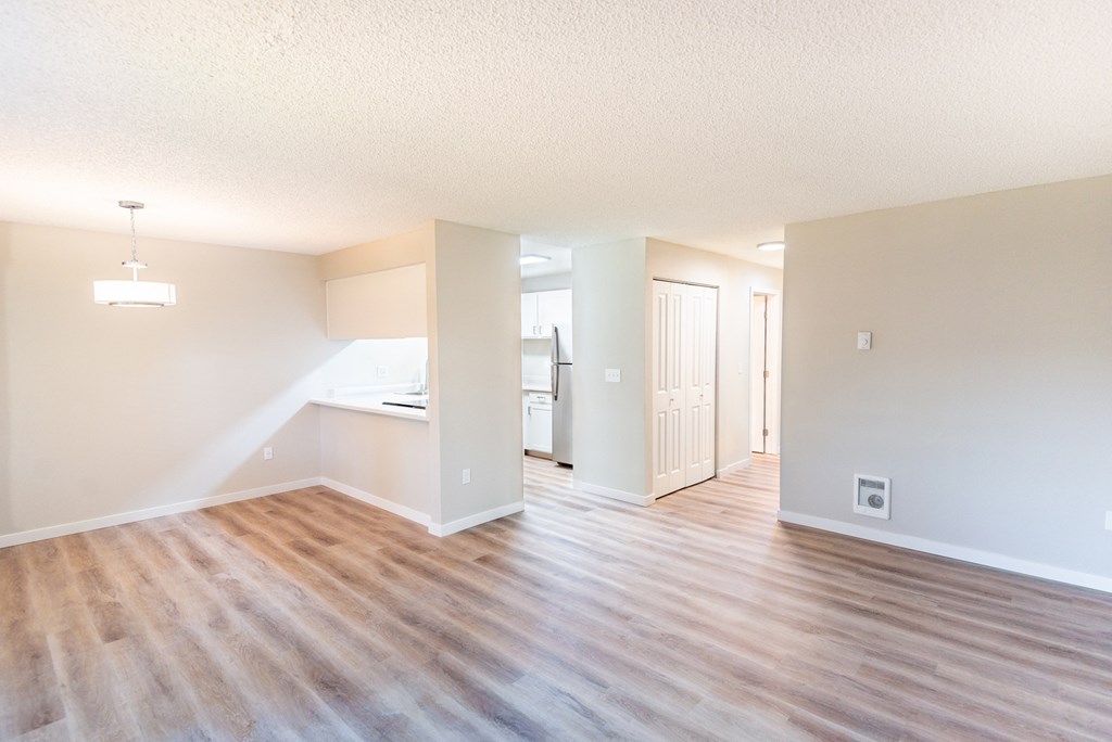 an empty living room and kitchen with a wood floor