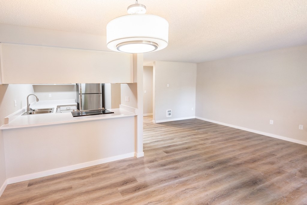 an empty living room and kitchen with a wood floor