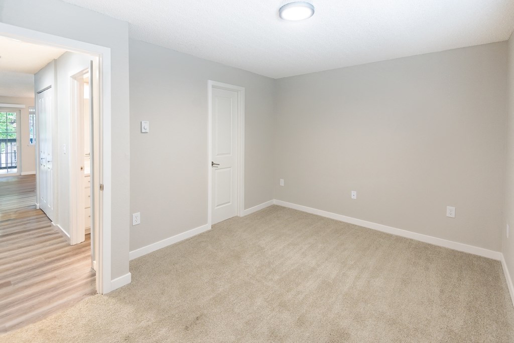 an empty living room with carpet and a door to a hallway