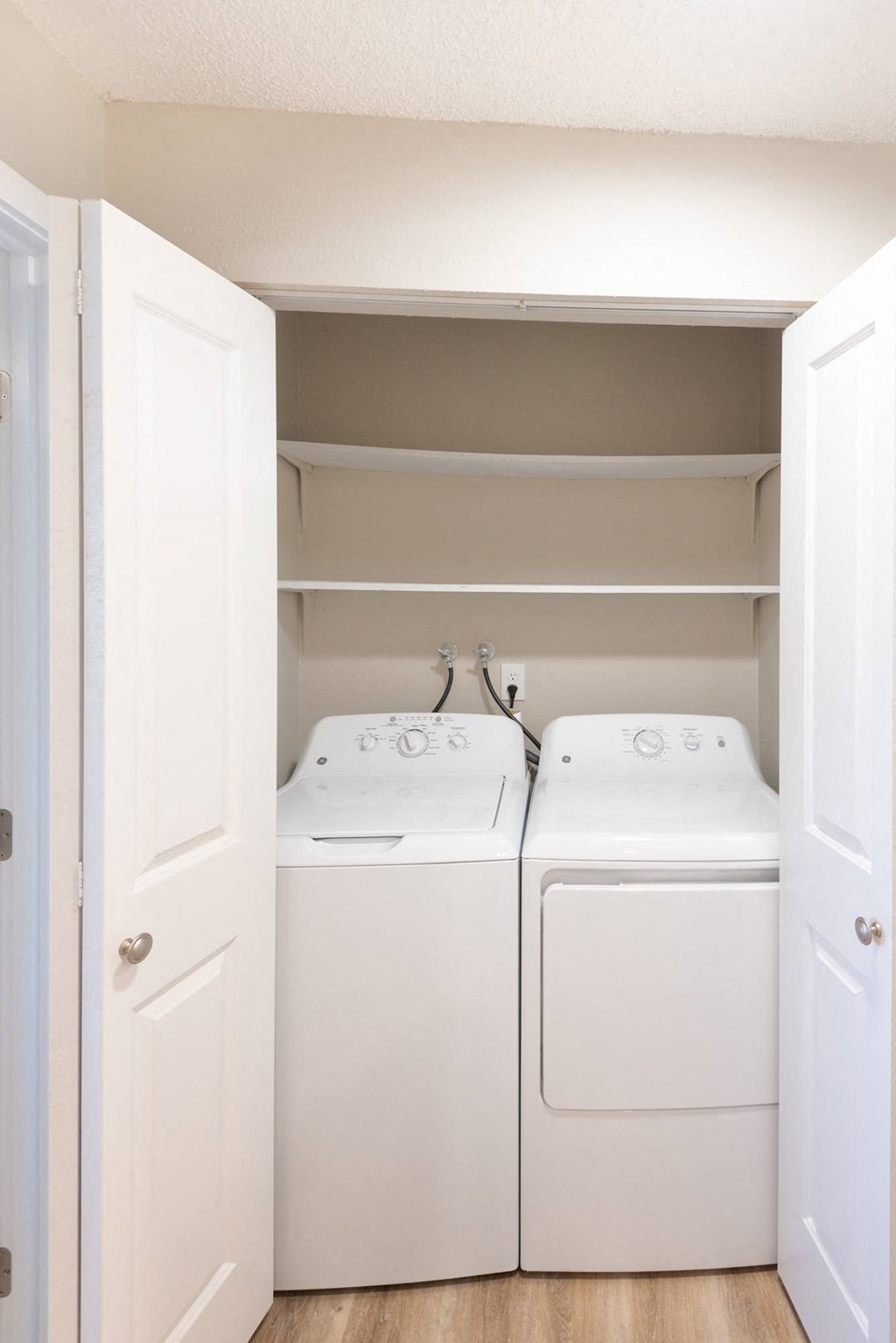 a washer and dryer in a laundry room with white cabinets