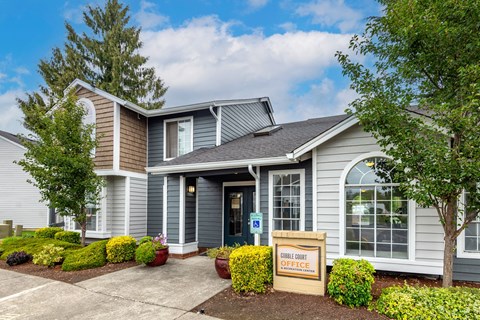 a gray house with a sign in front of it