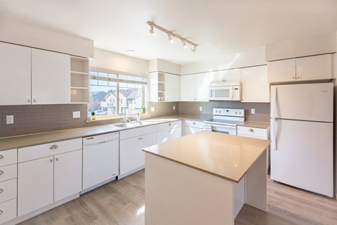 a large kitchen with white cabinets and appliances and a counter top