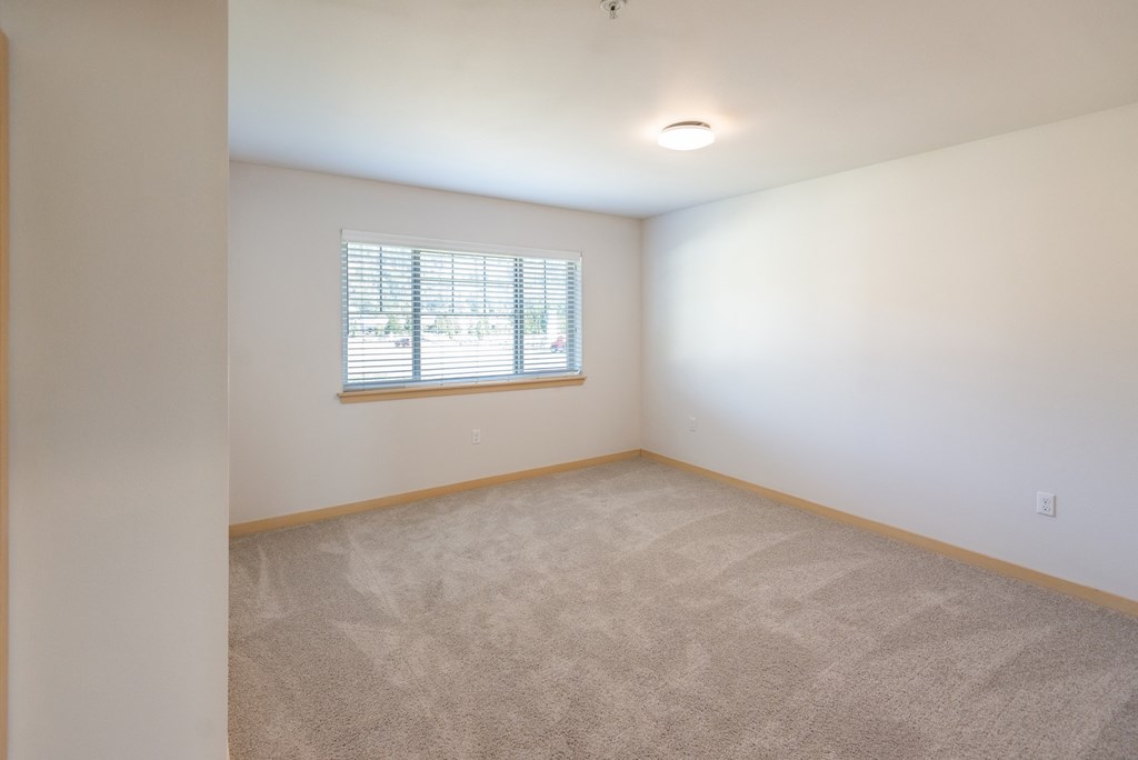 a bedroom with white walls and a window