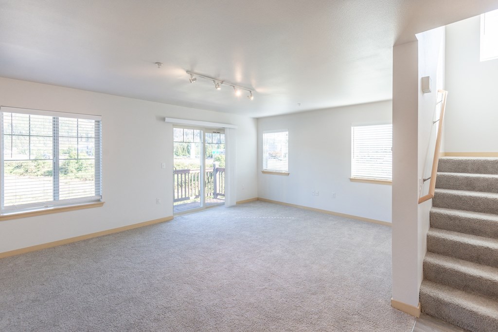 an empty living room with a staircase leading up to a balcony