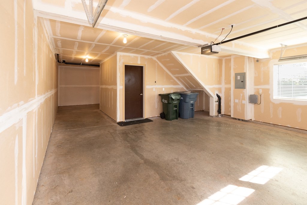an empty garage with a door and two trash cans