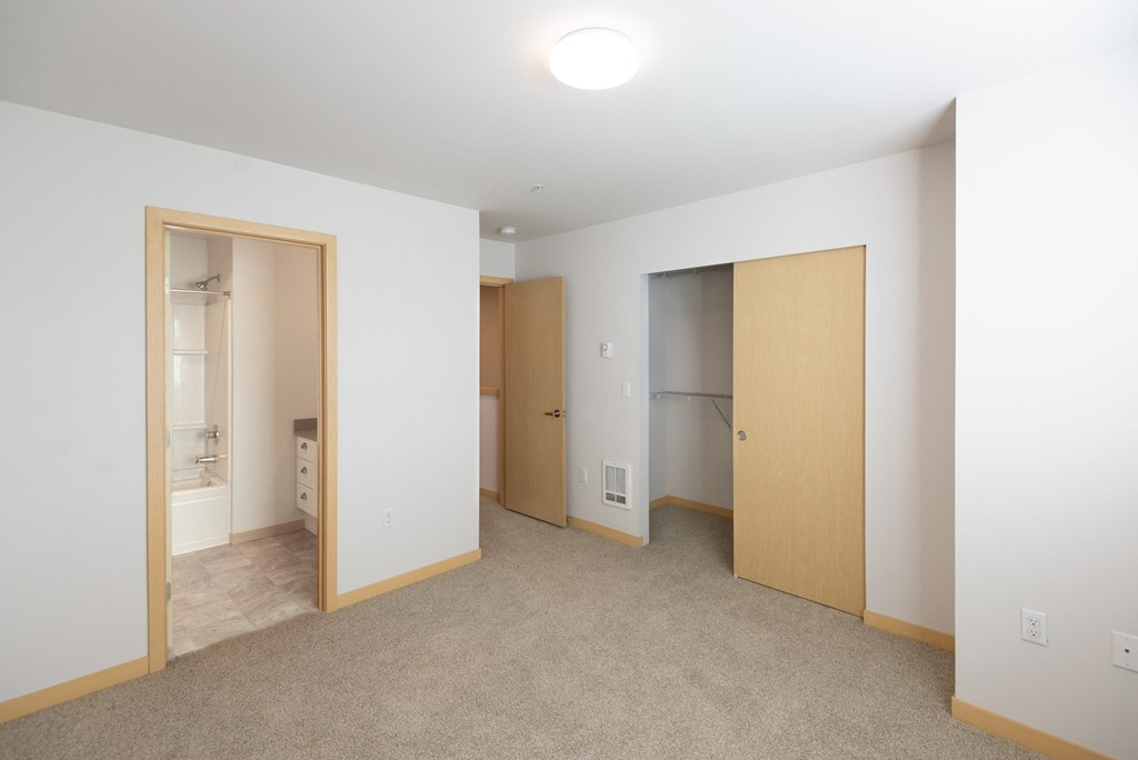 a bedroom with white walls and a beige carpet