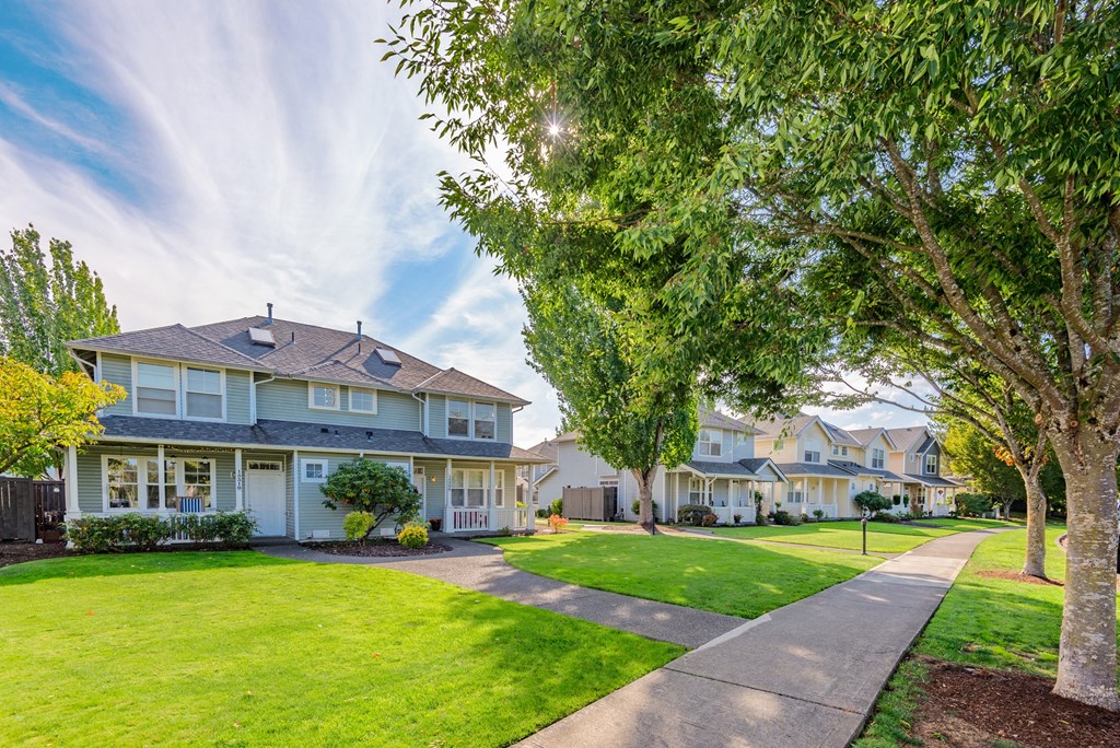 a row of houses on a sidewalk with grass and trees