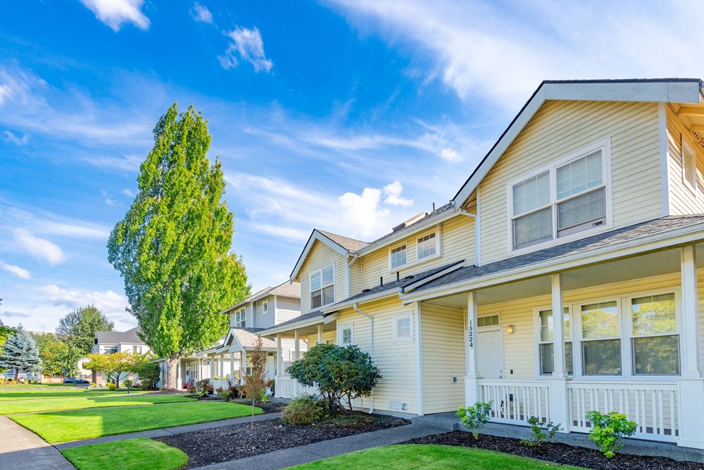 a row of yellow houses with green grass and a blue sky