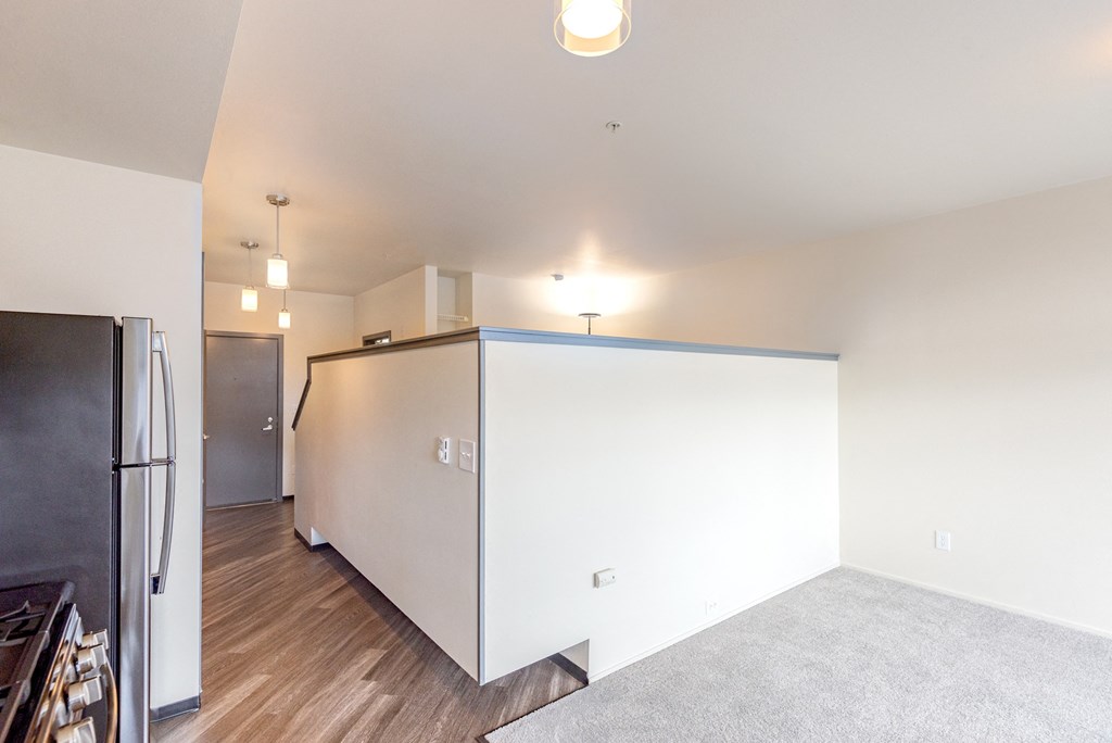 a kitchen and living room with a white wall and a refrigerator