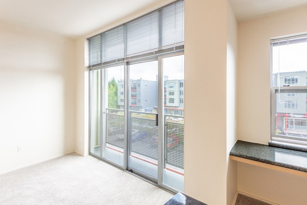an empty living room with large windows and a balcony