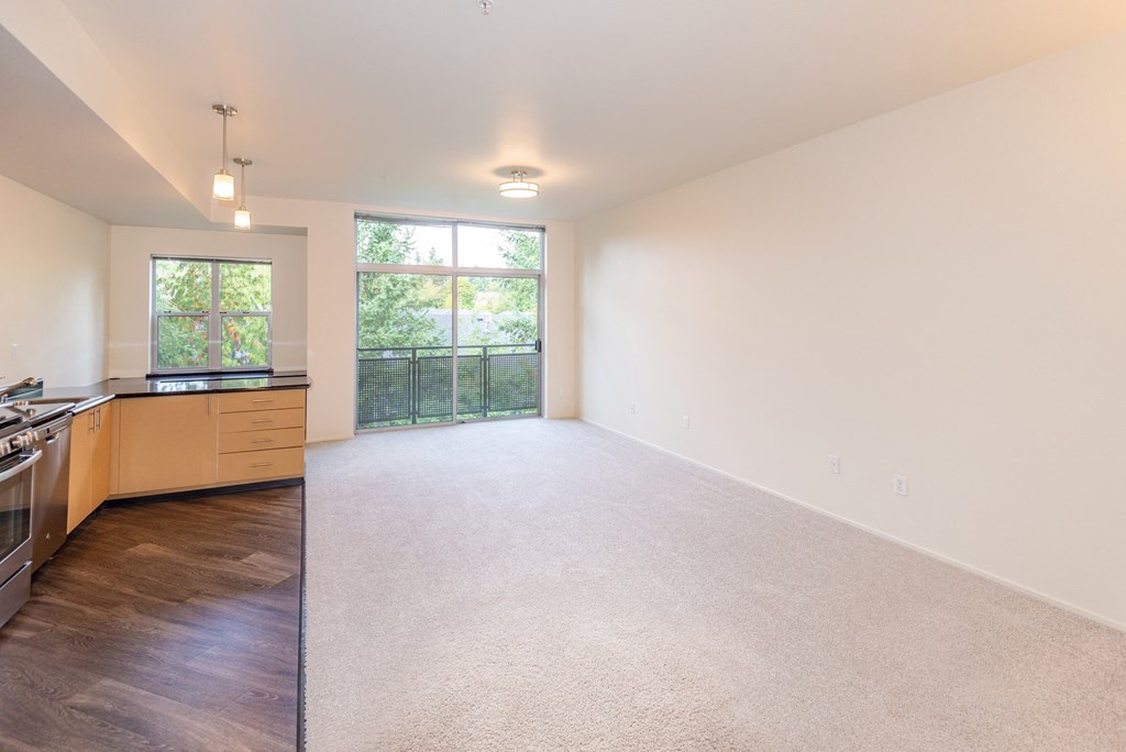 a spacious living room with a kitchen and a large window