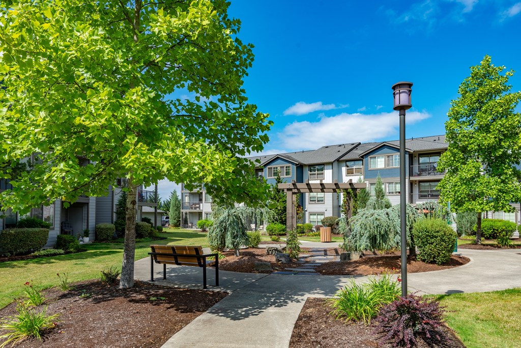 a park with trees and a bench in front of an apartment building