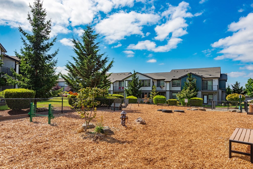 a courtyard with benches and trees in front of an apartment building