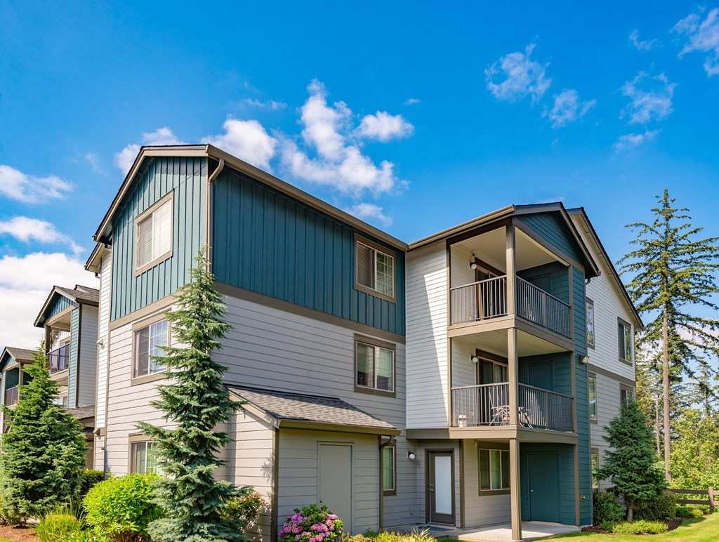 the view of two story apartment buildings with balconies and trees
