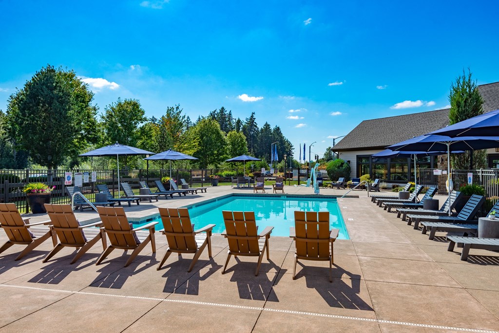 our resort style pool is filled with lounge chairs and umbrellas