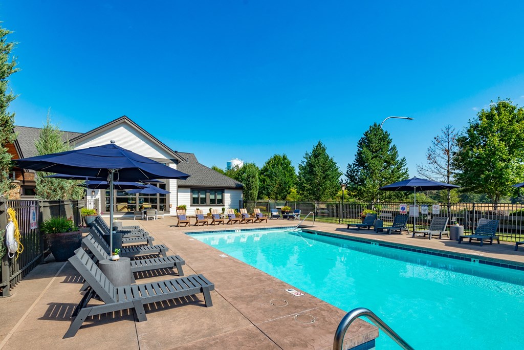 our resort style swimming pool with lounge chairs and umbrellas