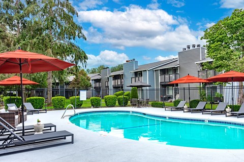 a swimming pool with umbrellas in front of apartment buildings
