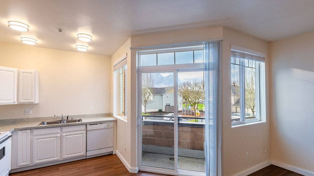 A kitchen with white cabinets and a view of the outside through the glass doors.