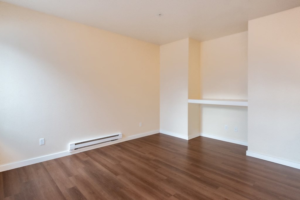 A room with wooden flooring and a wall-mounted air conditioner.
