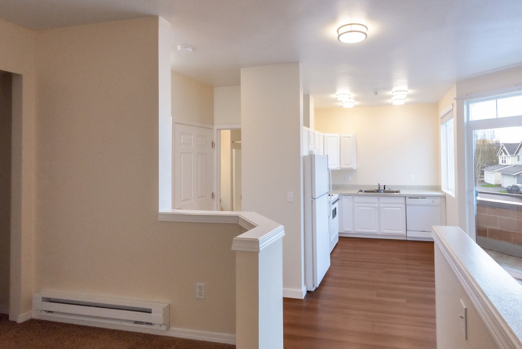 A kitchen with white cabinets and a window overlooking a street.