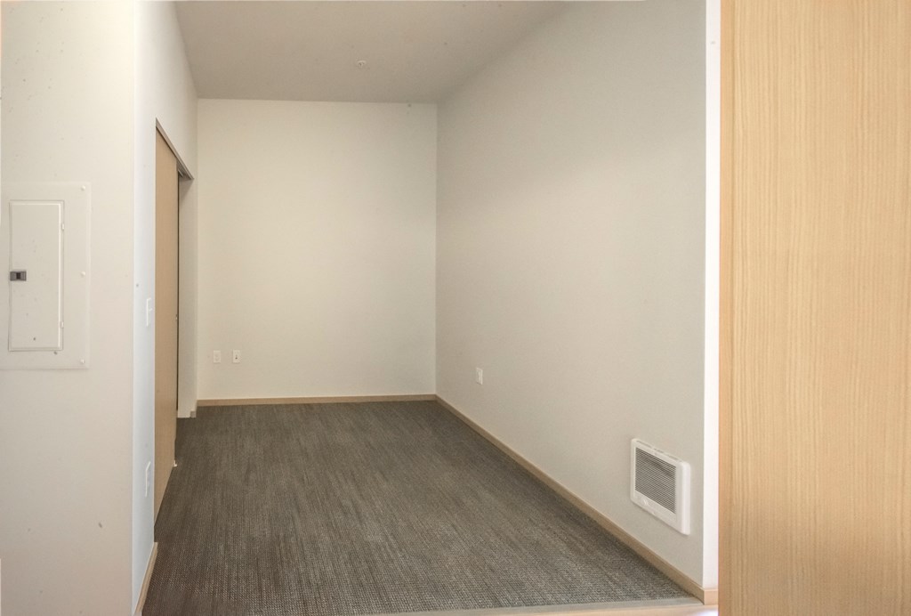 an empty living room with white walls and a gray carpet