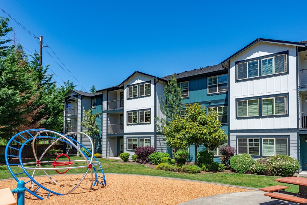 A playground with a blue swing set in front of apartment buildings.