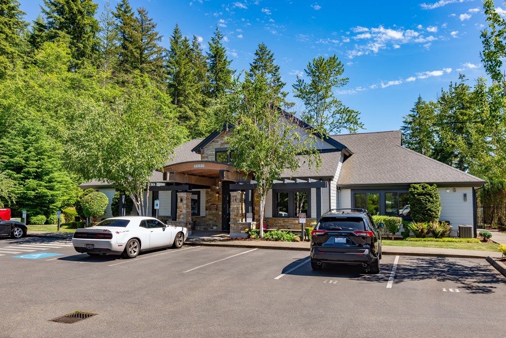 A white car is parked in front of a building with a black car parked behind it.