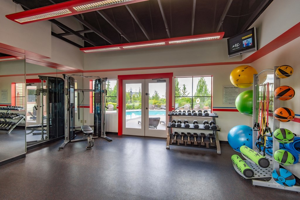 a workout room with weights and a pool in the corner of a building
