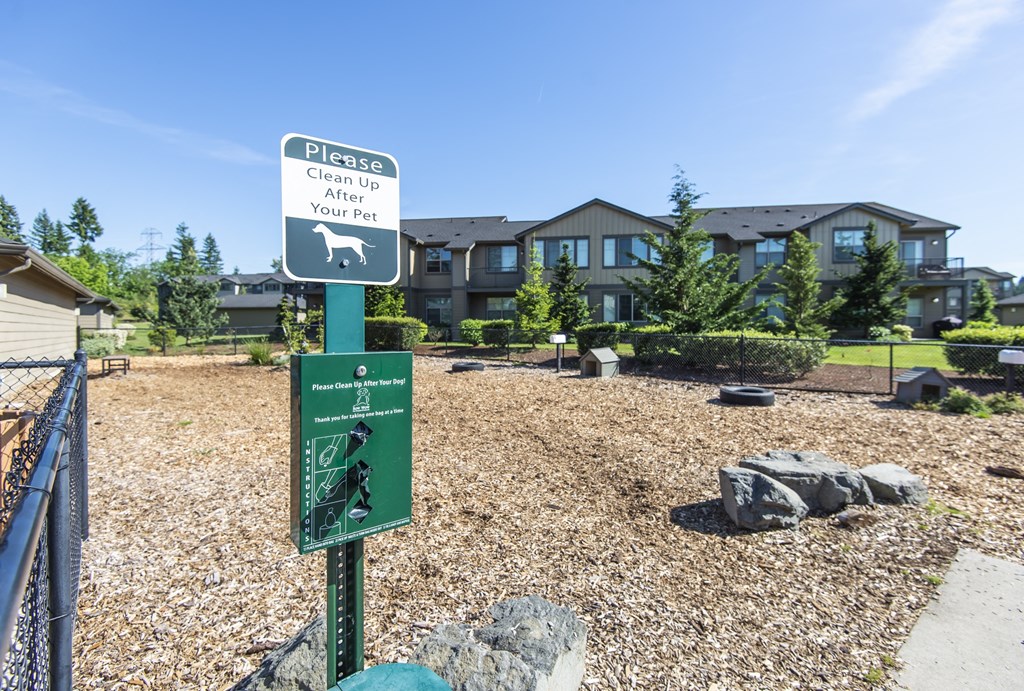 a sign in a park with a house in the background