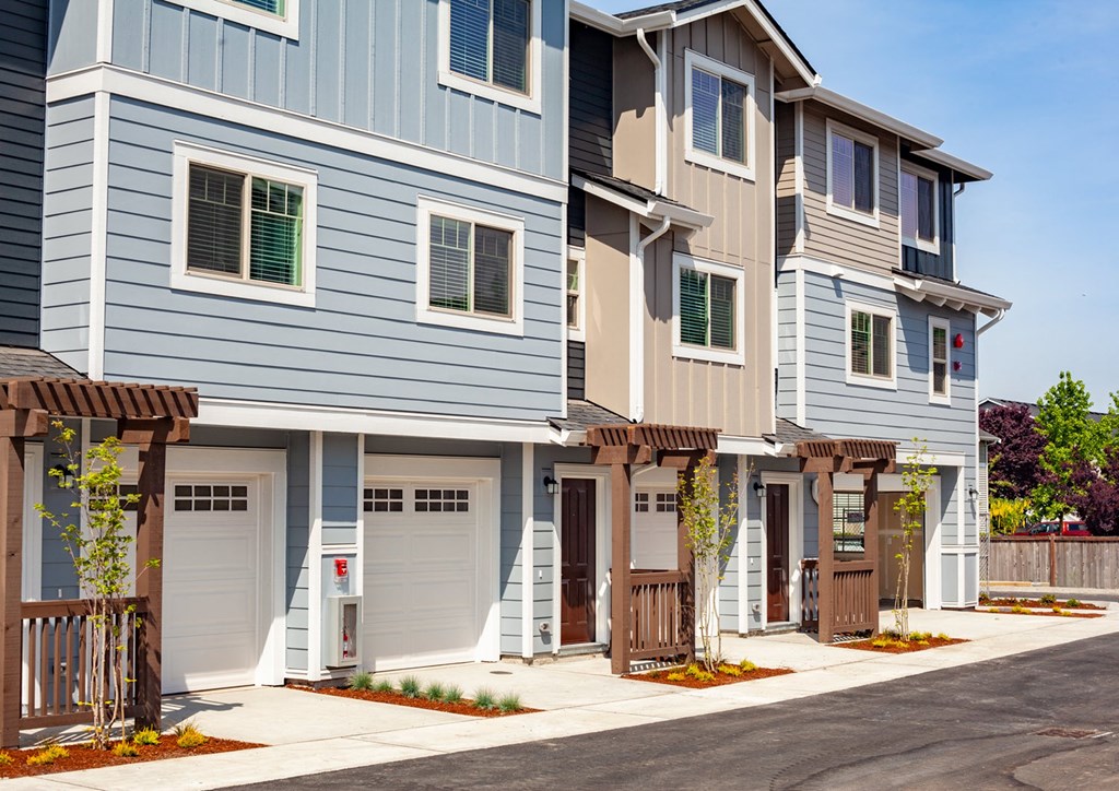 a row of townhomes with blue siding and brown doors