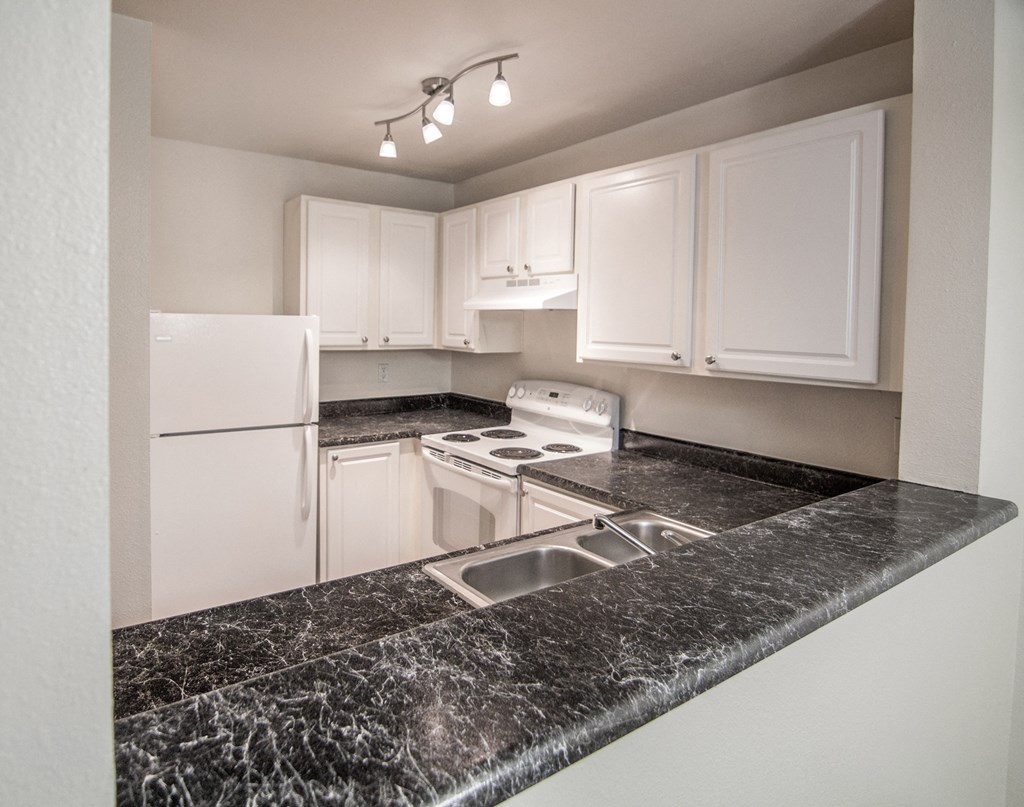 a kitchen with granite countertops and white appliances