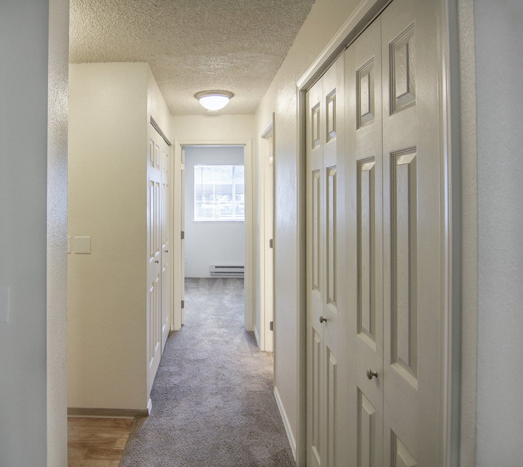a hallway with white doors and a window