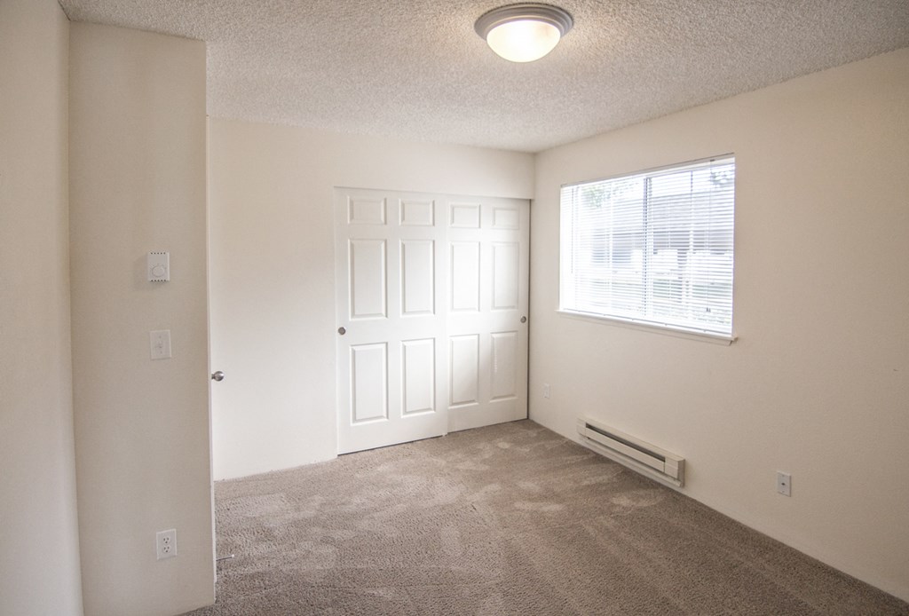an empty bedroom with a window and a door