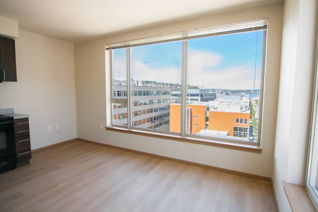an empty living room with a large window and wooden floors
