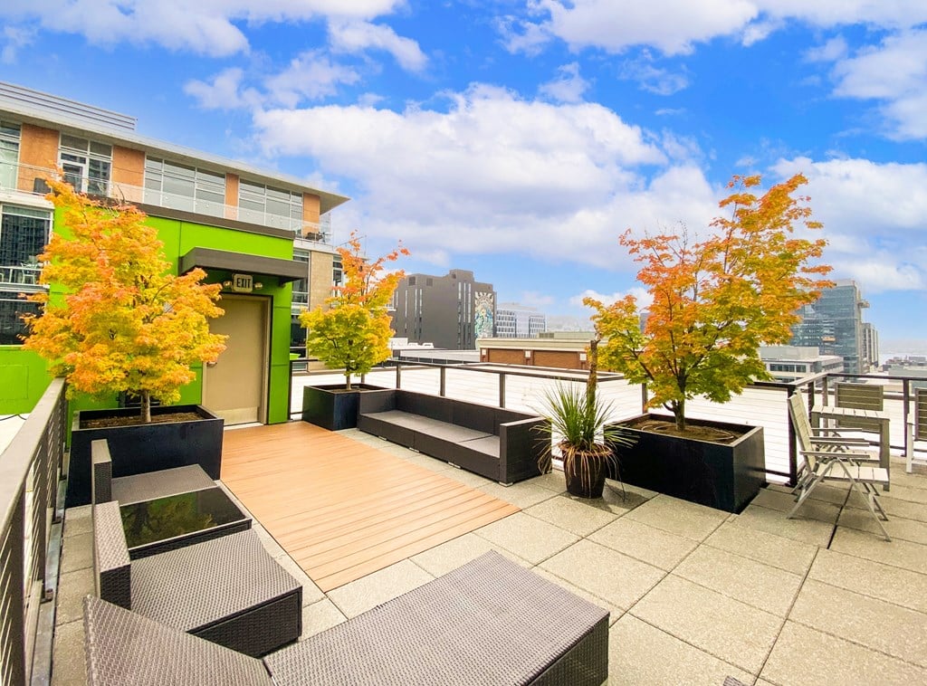 a rooftop terrace with tables and chairs and a city skyline in the background