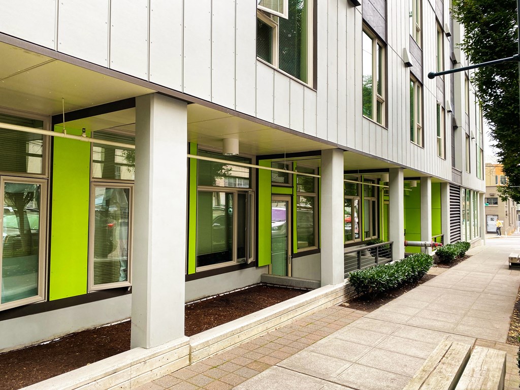a building with green windows and a sidewalk