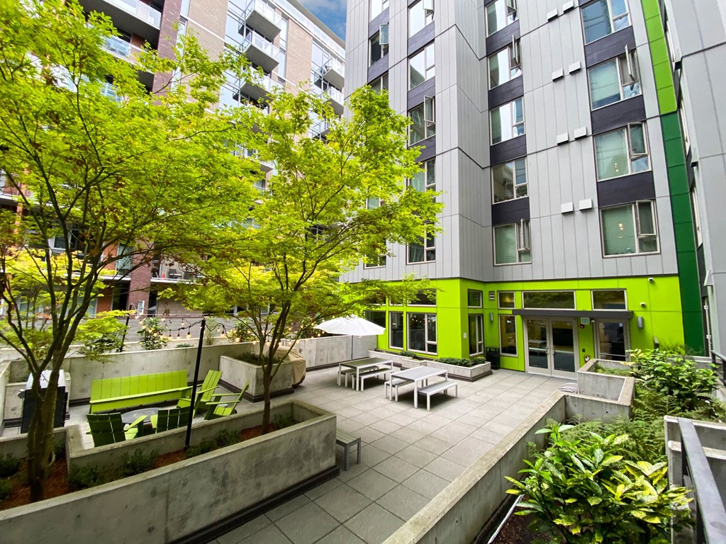 a courtyard with benches and trees in front of a building