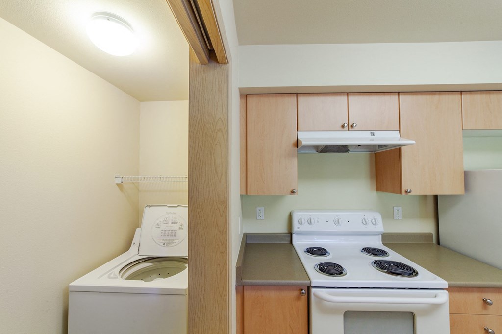 a kitchen with a stove and a washer and dryer in it