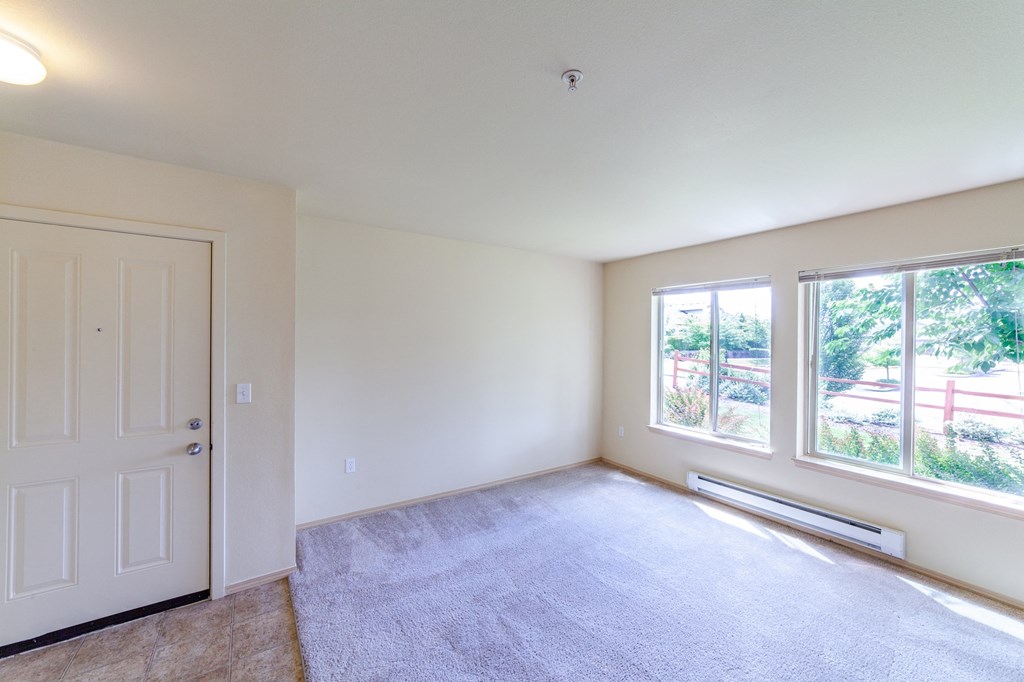 an empty living room with a white door and large windows