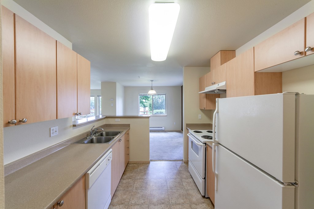 an empty kitchen with white appliances and wood cabinets
