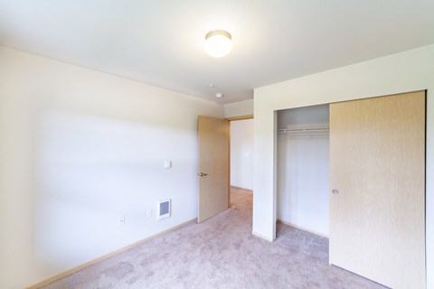 a bedroom with white walls and a door to a closet