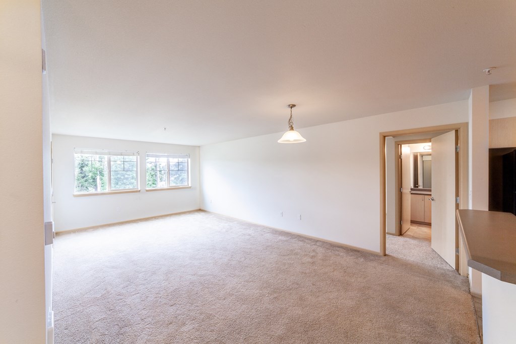a spacious living room with white walls and carpet