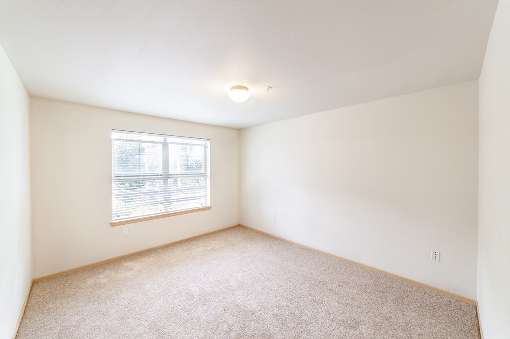 a bedroom with white walls and a window