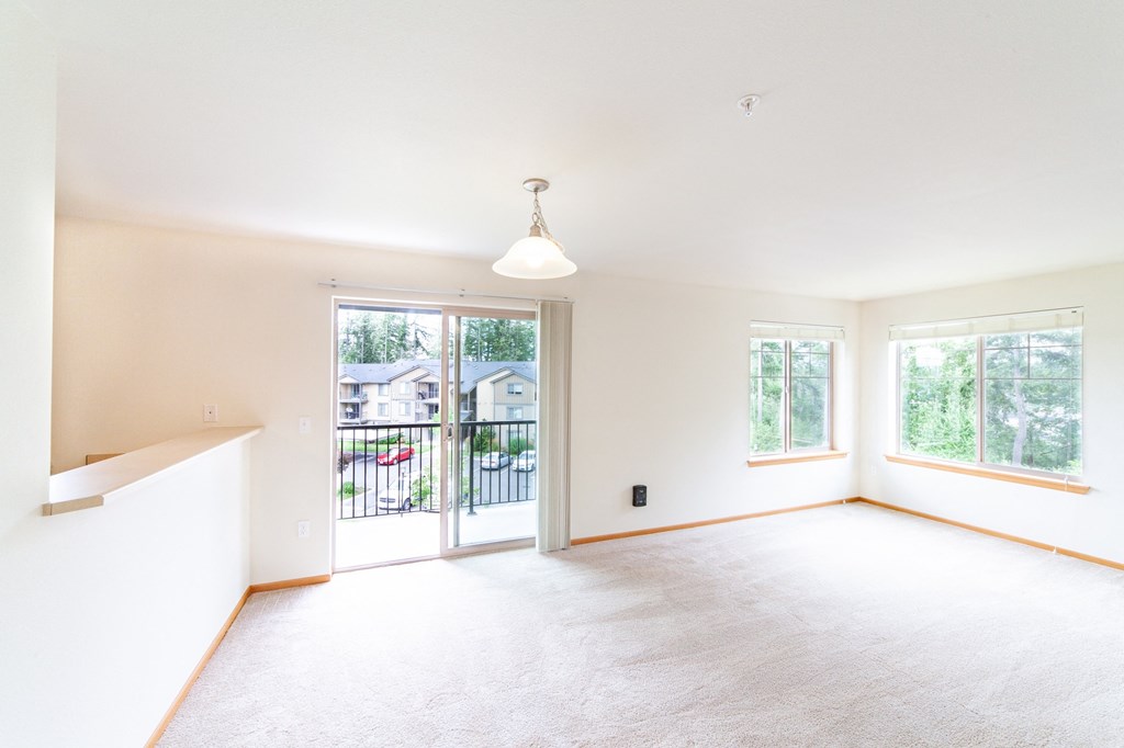 an empty living room with a sliding glass door and a balcony