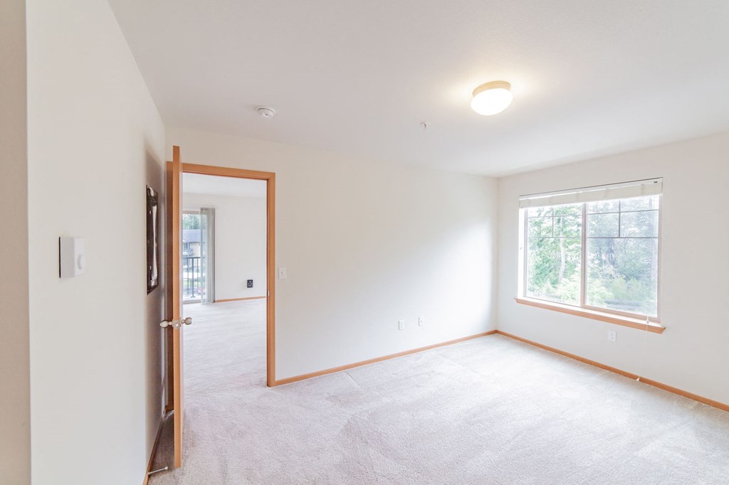 a bedroom with white walls and a large window