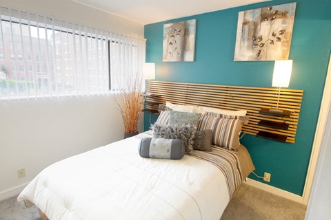 a bedroom with a bed and a blue wall and a window