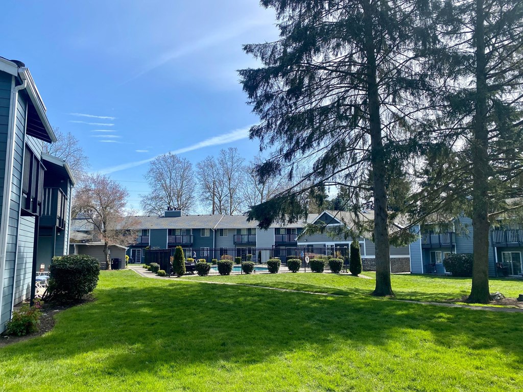 a row of houses with a green lawn and trees