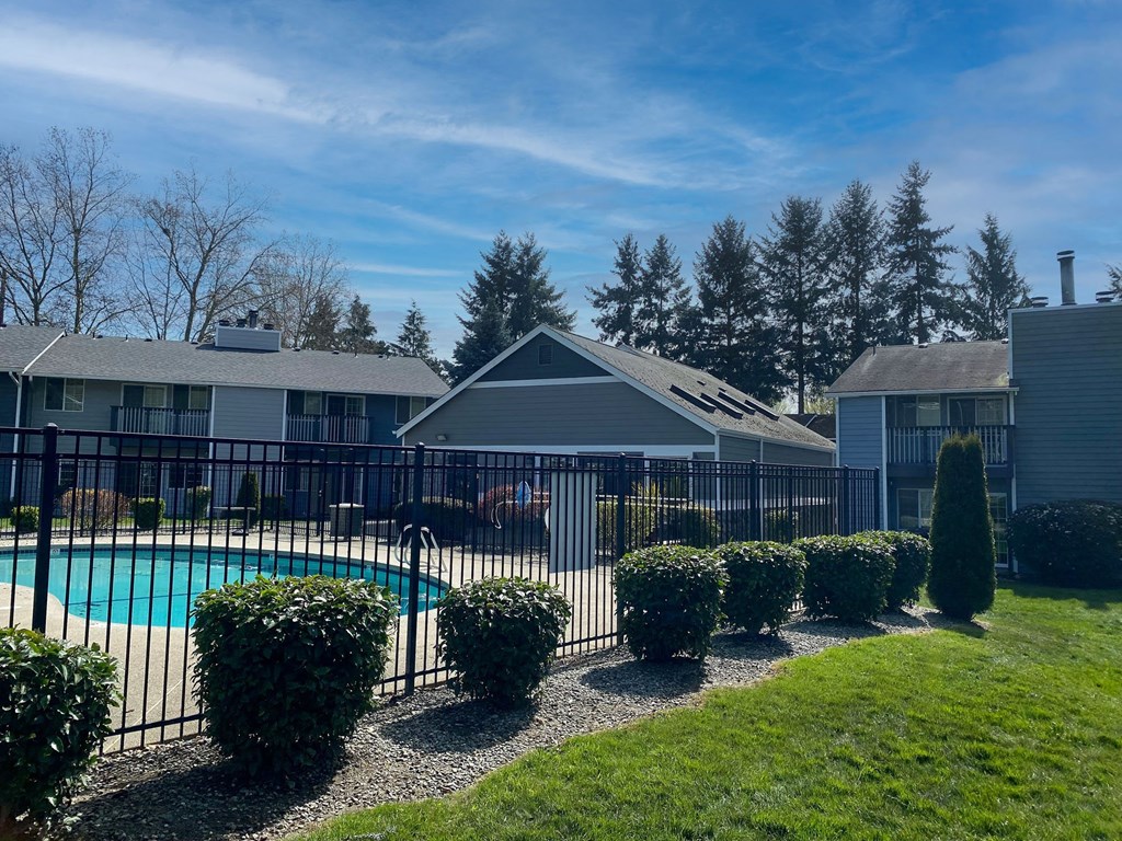 a swimming pool in front of a house with a fence