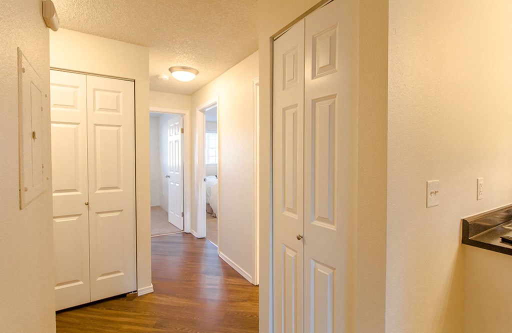 a hallway with white closets and a door to a bedroom